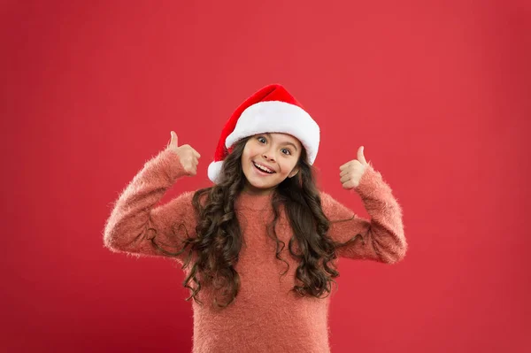 A divertir-se na melhor festa. Pequeno Pai Natal. sentir-se feliz com o ano novo. tempo para o feriado de Natal. Menina pequena em chapéu de santa. alegre criança vermelho fundo. moda de criança de inverno. feriado de inverno favorito — Fotografia de Stock