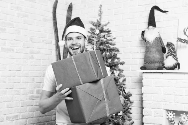 Kerst macho in rode hoed glimlach met ingepakte cadeautjes — Stockfoto