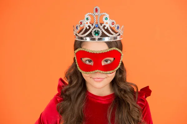 Visit public event anonymously. Winter new year party. Winter carnival. Incognito mode. Girl wear mask and crown orange background. Winter event and entertainment. Princess award. Royal and luxury
