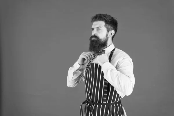 Das past perfect. elegante banketkeuken. zelfverzekerde barman. mannelijk koken. Een man met een baard. Brutale ober in de keuken. volwassen man baard rode achtergrond. bekwame dienaar. hipster kok in uniform — Stockfoto