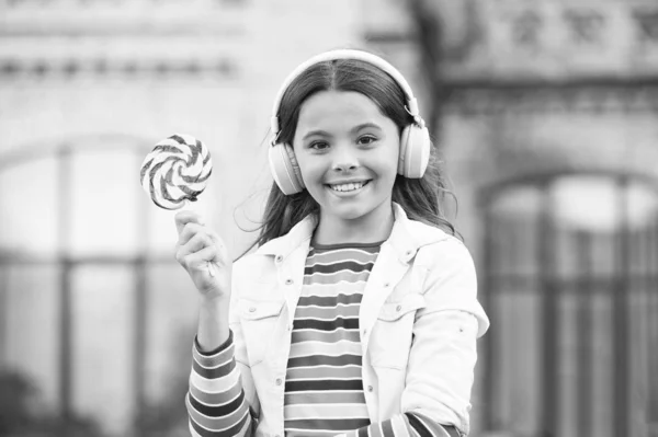 Chico feliz cantando dulce dulce micrófono. Feliz infancia. Auriculares infantiles para niños con caramelos de piruleta. Niño feliz con dulces al aire libre divirtiéndose. Calorías y energía. La colegiala merece el postre. Dulce remix — Foto de Stock