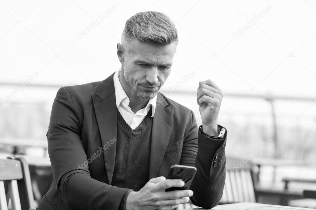 Mobile is lifestyle not technology. Mature businessman use mobile device in cafe. Handsome man hold mobile phone in hand. Mobile business communication. Modern life