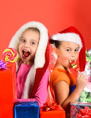 Hediye kutuları ve lolipoplarıyla Noel Baba şapkalı çocuklar.