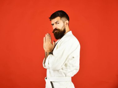 Kırmızı arka planda beyaz kimonolu sakallı adam..