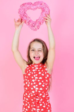 Sevgililer günü, bayram kutlaması. Pembe arka planda ellerini kaldırmış çocuk göz kırpıyor.