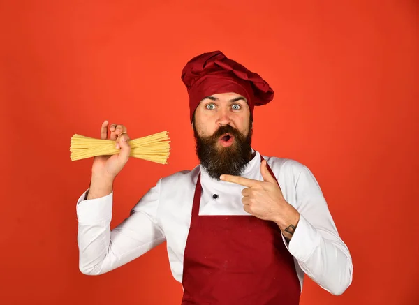 Kook met verrast gezicht in bordeauxrode hoed en schort — Stockfoto