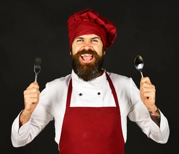 Man met baard houdt keukengerei op zwarte achtergrond. — Stockfoto