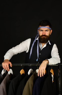 Elbise rafında sakallı bir adam. Resmi kıyafet seçimi.