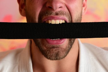 Adam siyah kimono kemerini ısırıyor, yaklaş. Karate dövüşçüsü