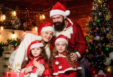 Yeni yıl partisinin tadını çıkarıyorum. Noel Baba şapkalı küçük çocuklar ve ebeveynler. Mutlu noeller. Anne ve baba çocukları sever. Portre seven aile. Bir sürü Noel hediyesi kutusu var. Mutlu aile yeni yılı kutluyor.