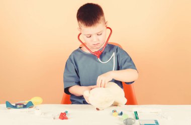 Çocuk küçük doktor meşgul masada tıbbi aletler ile oturup. Tıbbi muayene. Tıp konsepti. Teddy Bear için tıbbi prosedürler. Çocuk sevimli çocuk gelecek Doktor kariyer. Hastane işçisi. Sağlık