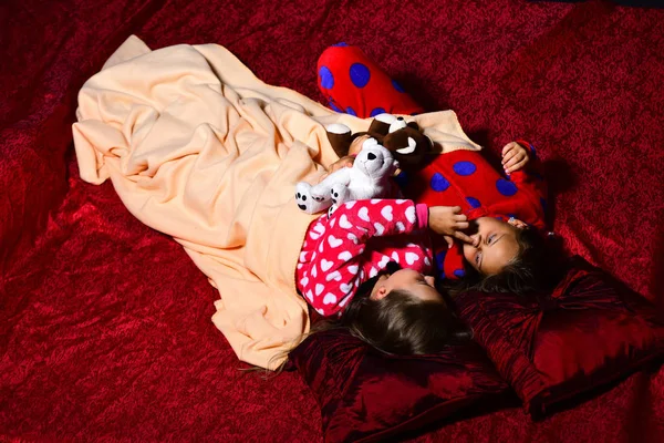 Barn i pyjamas spela i sängen på mörk bakgrund. — Stockfoto
