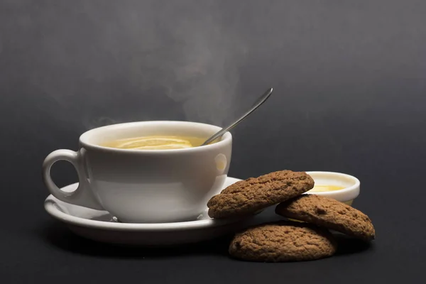 Cookies near tea on dark grey background