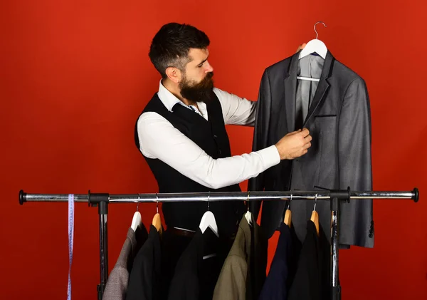 Помічник магазину або продавець налаштовує костюм біля вішалок для одягу . — стокове фото