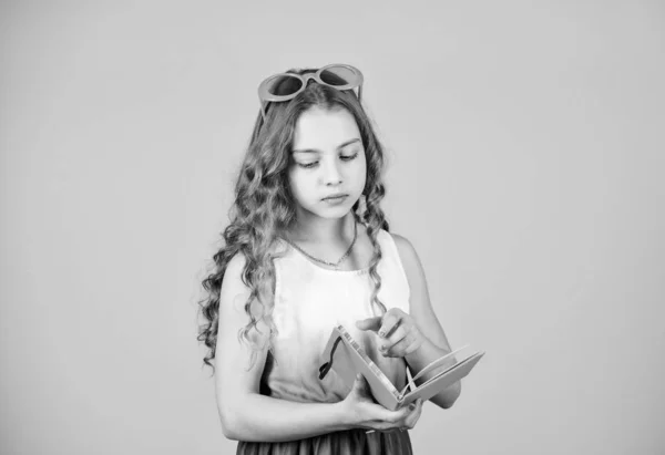 Pequena menina feliz em óculos com notebook. pequena menina beleza escrever suas memórias. notas do diário. livro de leitura. Moda de verão. fazer planos para férias de verão e férias. estudante ler livro — Fotografia de Stock