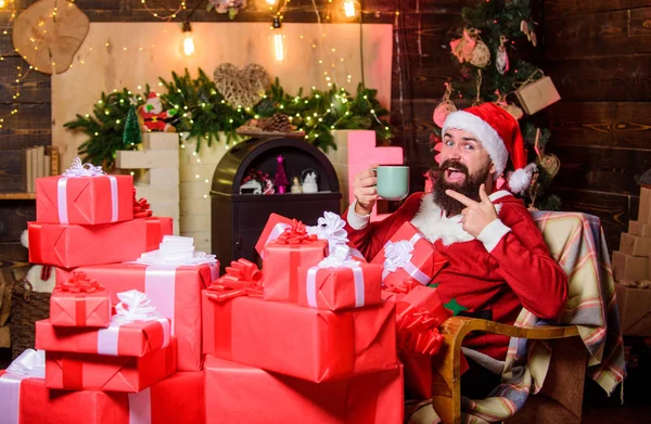 Побей Рождественскую лихорадку. Счастливчик пьет чай. Молоко для Санты. бородатый мужчина с настоящей коробкой. Подарки на Рождество. Рождественские распродажи. Счастливого Рождества. С Новым годом. Красный костюм Санты — стоковое фото