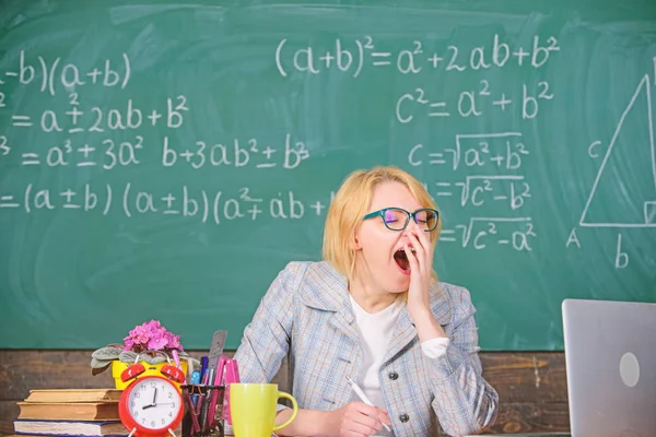 Condiciones de trabajo para los profesores. Condiciones de trabajo que deben tener en cuenta los futuros profesores. Trabaja mucho más allá del día escolar actual. Mujer cansado profesor sentarse mesa aula pizarra fondo — Foto de Stock