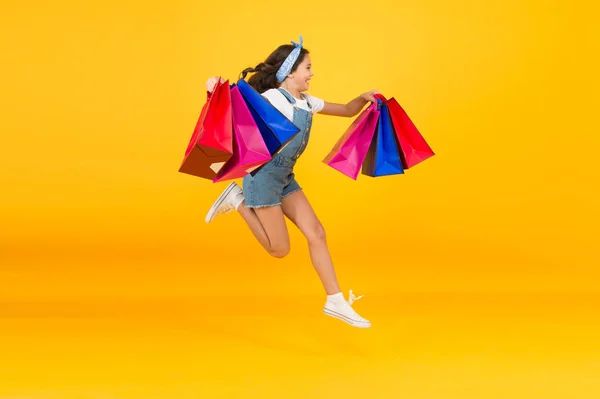 Energetic child jump with heavy bags. holiday gifts in packages. cyber monday. hurry up its total sale. Kids fashion. Sales and discounts. happy small girl after successful shopping. Time to shop — Stock Photo, Image