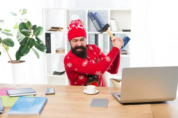 Rossz hírek. Dühös hipster kalapáccsal ütötte meg a laptopot. A szakállas férfi karácsonyi ruhában dühös lett. Mérgesnek lenni az üzleti gondok miatt. Stressz a munkahelyen. Dühös vagyok. Rossz hangulat — Stock Fotó
