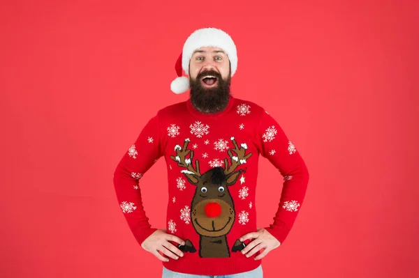 Holiday season mood. bearded man santa hat red background. merry christmas. ready for xmas party. happy new year. cheerful hipster funny knitted sweater. warm clothes in cold winter weather — Stock Photo, Image