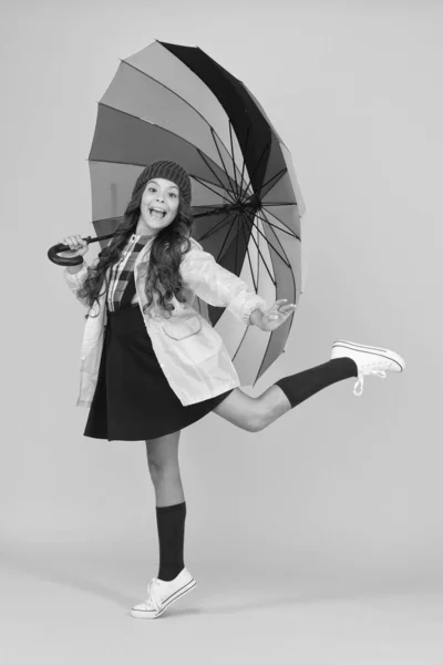 Yağmurda dans etmek. Küçük mutlu çocuk sarı arka planda renkli bir şemsiye tutuyor. Yağmurlu bir sonbahar gününde çocukluk aktiviteleri. Erken çocukluk eğitimi. Mutlu bir çocukluk okulu. Çocukluğum Hakkım — Stok fotoğraf