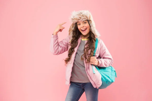 Escola de Qualidade. pequena menina feliz de volta para a escola. férias de inverno. criança roupas quentes fundo rosa. chapéu earflap criança feliz. estudante com saco ir para casa. Fim do ano lectivo. Não há mais exames. — Fotografia de Stock