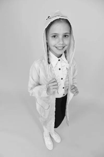 Su aspecto ilumina incluso los días más nublados. Adorable chica con mirada de otoño sonrisa sobre fondo amarillo. Niño feliz tiene mirada glamurosa en impermeable. Aspecto de moda de un niño pequeño — Foto de Stock