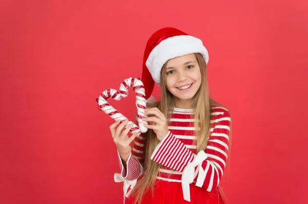 Dulce y encantador. tiempo de compras de Navidad. feliz año nuevo celebración. fiesta festiva en color rojo. dulce felicidad de la infancia. Pequeña chica diviértete. Santa elfo niño caña de azúcar. Navidad decoración de vacaciones —  Fotos de Stock