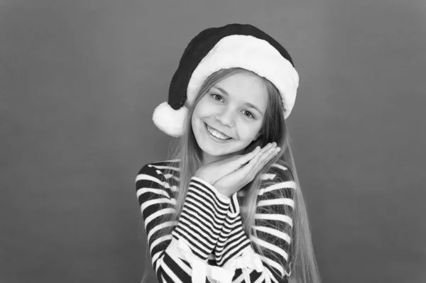 La Navidad es tiempo de complacer. Niño feliz usar traje de Navidad fondo rojo. Niña pequeña con sonrisa de santa mirada en la víspera de Navidad. Feliz navidad. Feliz Año Nuevo — Foto de Stock