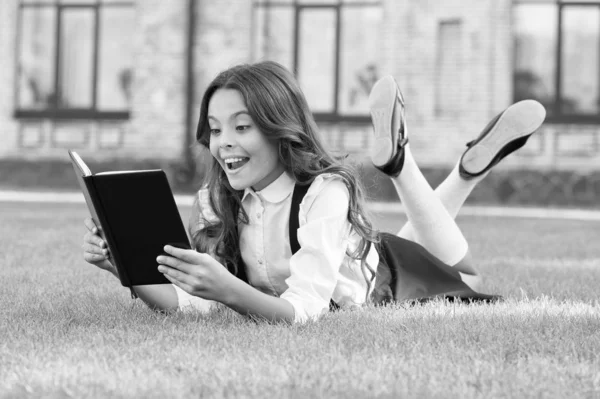 Lesson on fresh air. Cute small child reading book outdoors. Educational book. Literature for kids. Schoolgirl school uniform laying on lawn with favorite book. Bookworm concept. Access to knowledge — Stock Photo, Image