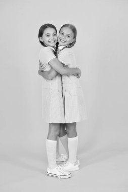 Eski usul. Çocuk modası. Mutlu arkadaşlar sarı arka plana sarılır. Moda güzeli. çocukluk mutluluğu. Eski okul üniformalı küçük kızların kardeşliği. Klasik tarzda çocuklar. Aşk kucaklaşması