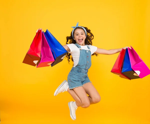 Настоящее счастье. счастливая маленькая девочка после удачного шопинга. энергичный ребенок прыгать с тяжелыми сумками. праздничные подарки в пакетах. Кибер понедельник. поторопитесь с полной продажей. Детская одежда. Продажи и скидки — стоковое фото