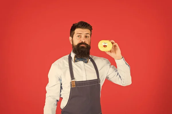 Hipster barbudo padeiro segurar donuts. Come donut. Humor alegre. Calorias de donut. Donut vitrificado. Homem barbudo e bem preparado com avental a vender donuts. Comida de donut. Produtos de panificação. Doces e bolos. Comida de plástico — Fotografia de Stock