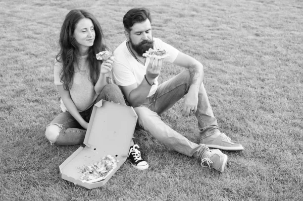 Sabor de la satisfacción. picnic de verano sobre hierba verde. pareja feliz comiendo pizza. Comida saludable. comida rápida. hombre barbudo hipster y adorable chica comer pizza. hambre. fin de semana familiar. pareja enamorada citas —  Fotos de Stock