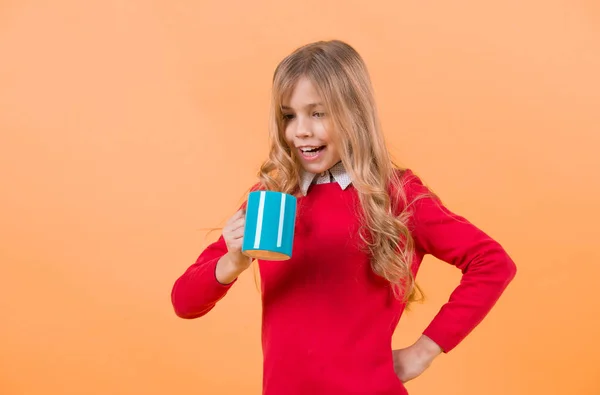 Kinderlächeln mit blauer Tasse auf orangefarbenem Hintergrund — Stockfoto