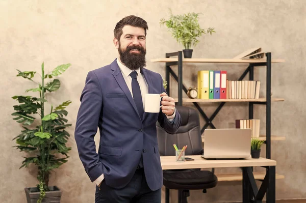 Мужчина бородатый бизнесмен держит кофейную чашку в офисе фон. Пить кофе расслабляющий перерыв. Босс наслаждается энергетическим напитком. Начните день с кофе. Успешные люди пьют кофе. Зависимость от кофеина — стоковое фото