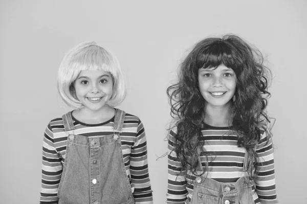 Moda y artística. Los niños felices usan pelucas de pelo de moda de fondo amarillo. Las niñas sonríen con aspecto de moda. Peluquería de moda. Moda y estilo —  Fotos de Stock