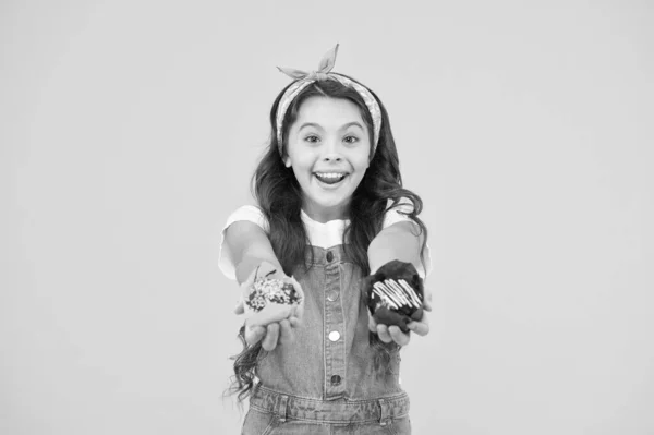 Concepto de panadería y confitería. Niña sostiene magdalenas acristaladas. Deliciosos pastelitos. Feliz infancia. Adorable niño sonriente con cupcakes sobre fondo amarillo. Café restaurante de comida. Deliciosas magdalenas —  Fotos de Stock