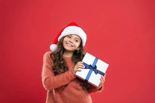 크리스마스 선물이야. 작은 소녀가 선물 상자. 새해 복 많이 받으세요. 크리스마스 연휴 파티. 산타 모자쓴 작은 소녀. 명랑 한 빨간 벽. 애들 쇼핑하는 거. 권투의 날이죠. 최고의 크리스마스 제공 — 스톡 사진