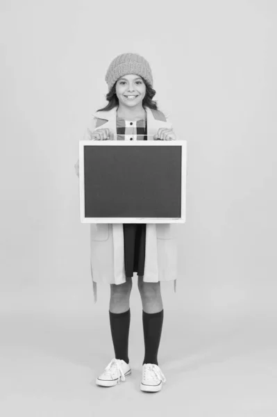 Providing information. Happy little girl hold blank blackboard for information yellow background. Small child smile with tidy chalkboard for school information. Information board, copy space — Stock Photo, Image