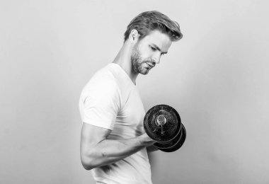 Yakışıklı adam egzersiz. Spor salonunda egzersiz yapmak. Dambılla egzersiz icra eden kaslı bir adam. Sporcu güçlü kasları antrenman. Spor ekipmanları. Fitness ve vücut geliştirme sporu. Spor yaşam tarzı. Spor motivasyonu