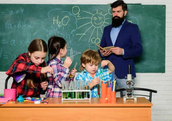 El club incluye una variedad de actividades con química. Educación del club escolar. Tema de nuestro club. Profesores y alumnos examinan tubos en el aula. Club temático de química. Interacción grupal y comunicación — Foto de Stock