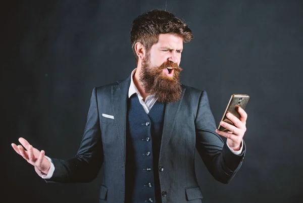 bad feedback from client. angry bearded man with smartphone. brutal caucasian hipster. businessman in suit. online and agile. Mature hipster with beard speak on phone. stressed man shouting