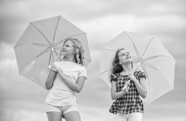 Crianças despreocupadas ao ar livre. Meninas amigas com guarda-chuvas céu nublado fundo. Liberdade e frescura. Previsão meteorológica. Pronto para qualquer tempo. Vento ou chuvoso estamos preparados. Mudança meteorológica — Fotografia de Stock