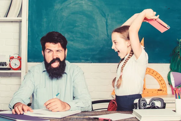 La ragazza arrabbiata odia leggere libri. Torniamo a scuola. Insegnamento privato. bambina con insegnante barbuto uomo in classe. lezione privata. giorno della conoscenza. Educazione a casa. studio figlia con padre — Foto Stock