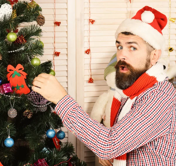 Guy in hat and scarf stands by fir tree — Stock Photo, Image