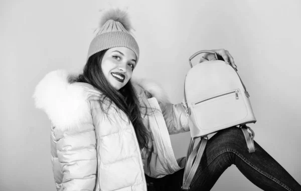 cheerful student. warm winter clothing. shopping. woman in beanie hat with backpack. happy winter holidays. flu and cold season. Leather bag fashion. girl in puffed coat. faux fur fashion
