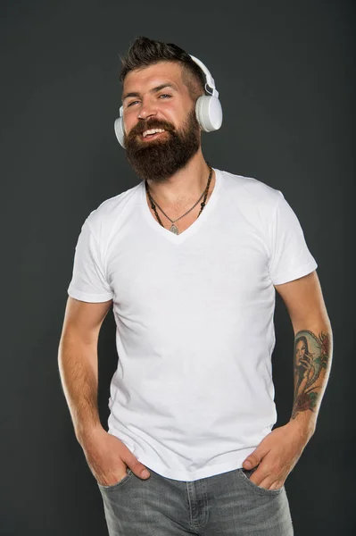 Feel happy. Happy hipster listen to music grey background. Bearded man enjoy happy melody playing in headphones. Be happy and listen to music. Pleasure and joy. Fun and entertainment