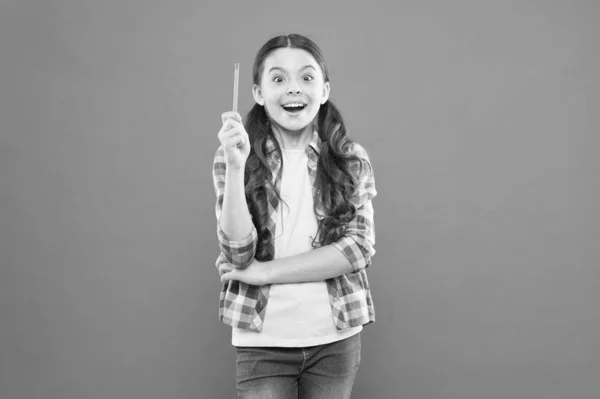 Yo soy el genio. Chica genio. La colegiala genio tiene una idea brillante sobre fondo naranja. Pequeño niño apuntando pluma hasta tener idea genio — Foto de Stock