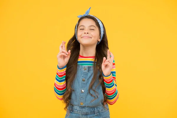 Sueño de niño. Concepto esperanzador. Niño pequeño con el pelo largo en la moda casual. Espero que sea lo mejor. Cree en sí misma. Niño lindo hacer deseo fondo amarillo. Pequeño niño mantener los dedos cruzados para la suerte — Foto de Stock